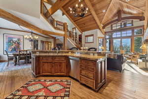 Kitchen with sink, a center island with sink, stainless steel dishwasher, a notable chandelier, and pendant lighting