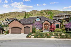 View of front of house with fence, brick siding, a garage, a mountain view, and concrete driveway