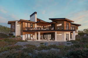 Rear view of house featuring a balcony, stone siding, and a patio area