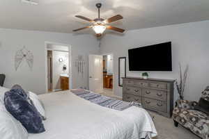 Bedroom with ceiling fan, ensuite bath, vaulted ceiling, and light carpet