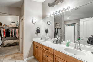 Bathroom with vanity, a shower with shower door, and tile patterned flooring