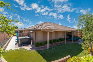 Back of property with a yard, a hot tub, and a patio area