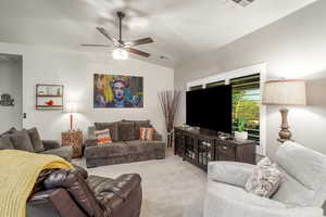 Living room with ceiling fan, light colored carpet, and lofted ceiling