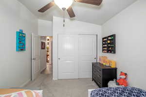 Carpeted bedroom with vaulted ceiling, a closet, and ceiling fan