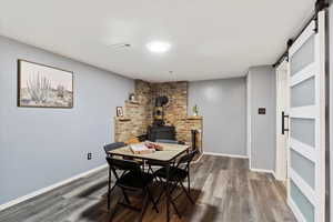 Dining space featuring a barn door, hardwood / wood-style floors, and a wood stove