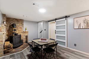 Dining space with dark hardwood / wood-style floors, a barn door, and a wood stove