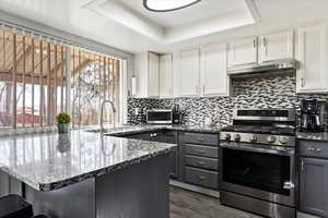 Kitchen with gray cabinetry, appliances with stainless steel finishes, and white cabinets