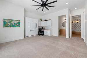 Interior space with ceiling fan, ensuite bathroom, and light carpet