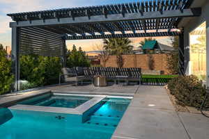 Pool at dusk featuring an in ground hot tub, a pergola, and a patio area