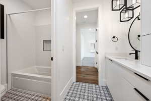 Full bath featuring vanity, tile patterned flooring, shower / bathtub combination, toilet, and baseboards