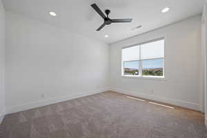 Spare room featuring carpet flooring, a ceiling fan, baseboards, and visible vents