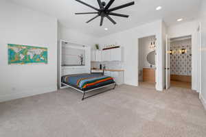 Carpeted bedroom featuring ceiling fan and ensuite bath