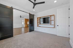 Unfurnished living room with baseboards, a ceiling fan, recessed lighting, and a barn door