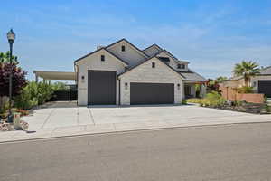 View of front facade featuring a garage, fence, driveway, and stone siding