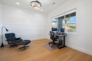 Home office with a chandelier and light hardwood / wood-style flooring