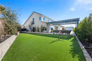 Rear view of property featuring a pergola and a lawn