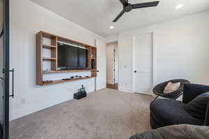 Carpeted living room featuring ceiling fan