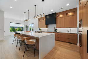 Kitchen featuring a sink, modern cabinets, light wood-style floors, and visible vents