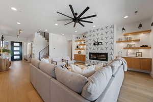 Living room with visible vents, stairs, ceiling fan, and light wood finished floors
