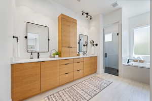 Full bathroom with visible vents, double vanity, a garden tub, a sink, and a stall shower