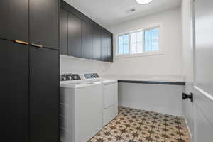 Clothes washing area with visible vents, washing machine and dryer, cabinet space, baseboards, and light floors