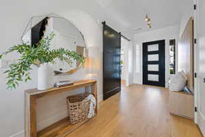 Foyer entrance featuring light wood-style floors, a barn door, and baseboards
