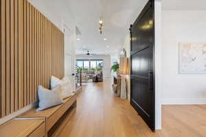 Hallway featuring recessed lighting, baseboards, a barn door, and light wood-type flooring