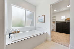 Full bath with visible vents, a spacious closet, and a garden tub