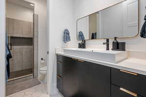 Bathroom featuring vanity, tile patterned floors, toilet, and a tile shower