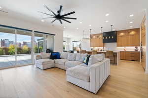 Living room featuring ceiling fan with notable chandelier and light hardwood / wood-style floors