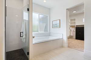 Bathroom featuring a bath, a walk in closet, a stall shower, and a healthy amount of sunlight