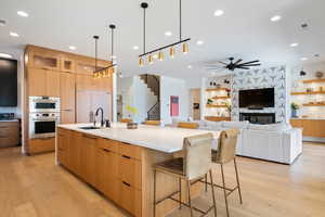 Kitchen featuring sink, light hardwood / wood-style flooring, a spacious island, and a kitchen bar