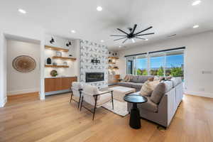 Living room with baseboards, a high end fireplace, light wood finished floors, and visible vents