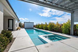 View of swimming pool with an in ground hot tub and a patio