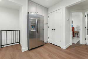 Kitchen with stainless steel fridge, light hardwood / wood-style floors, and gray cabinetry