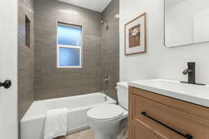 Full bathroom with tiled shower / bath, vanity, and toilet