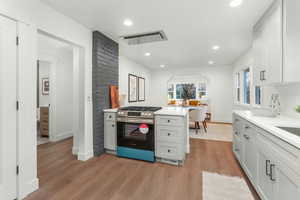 Kitchen featuring white cabinetry, stainless steel range with gas cooktop, and light hardwood / wood-style floors