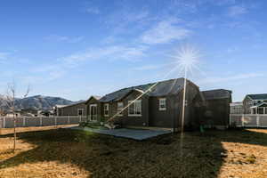 Rear view of property with a mountain view, a patio area, and a lawn