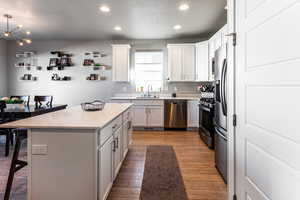 Kitchen with sink, appliances with stainless steel finishes, a kitchen breakfast bar, white cabinets, and a kitchen island