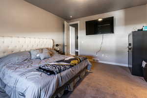 Carpeted bedroom featuring fridge and a textured ceiling