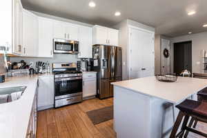 Kitchen with white cabinetry, a center island, appliances with stainless steel finishes, and a breakfast bar