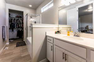 Bathroom with vanity, an enclosed shower, and wood-type flooring