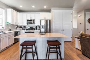 Kitchen featuring stainless steel appliances, a center island, sink, and white cabinets