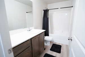 Full bathroom featuring vanity, toilet, wood-type flooring, and shower / bath combo with shower curtain