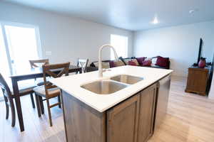 Kitchen with an island with sink, dishwasher, sink, and light wood-type flooring