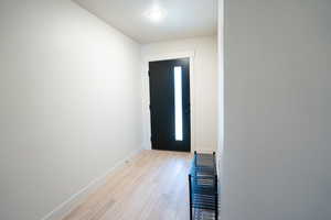 Doorway to outside with a textured ceiling and light hardwood / wood-style flooring