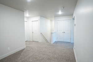 Hallway featuring light carpet and a textured ceiling