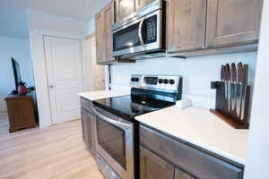 Kitchen featuring appliances with stainless steel finishes, dark brown cabinets, and light hardwood / wood-style flooring