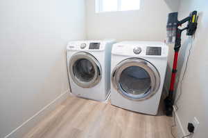 Washroom with washer and clothes dryer and light hardwood / wood-style floors