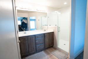 Bathroom featuring vanity, wood-type flooring, and a shower with door